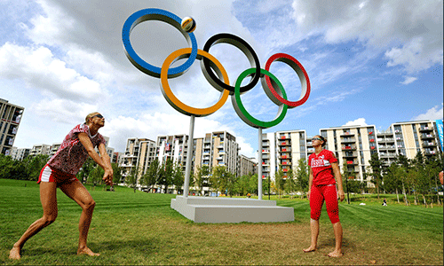 Two athletes playing volleyball at the Olympic rings outside the Olympic Village, London 2012.